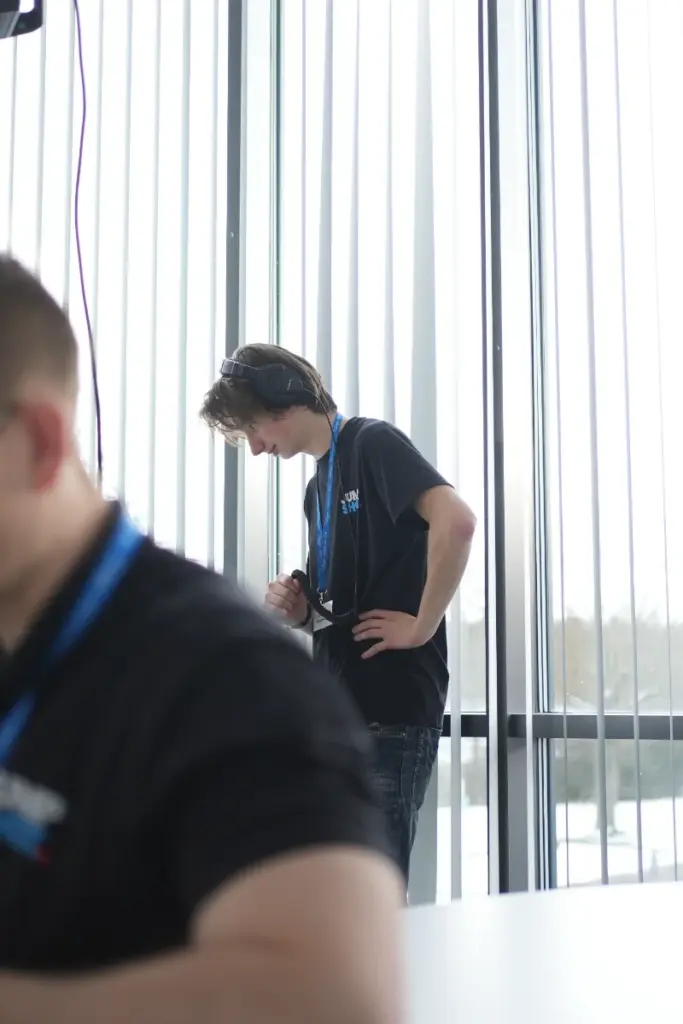 Person mit Kopfhörern arbeitet in einem hellen Büro der Medienagentur mit Blick auf die Stadt.